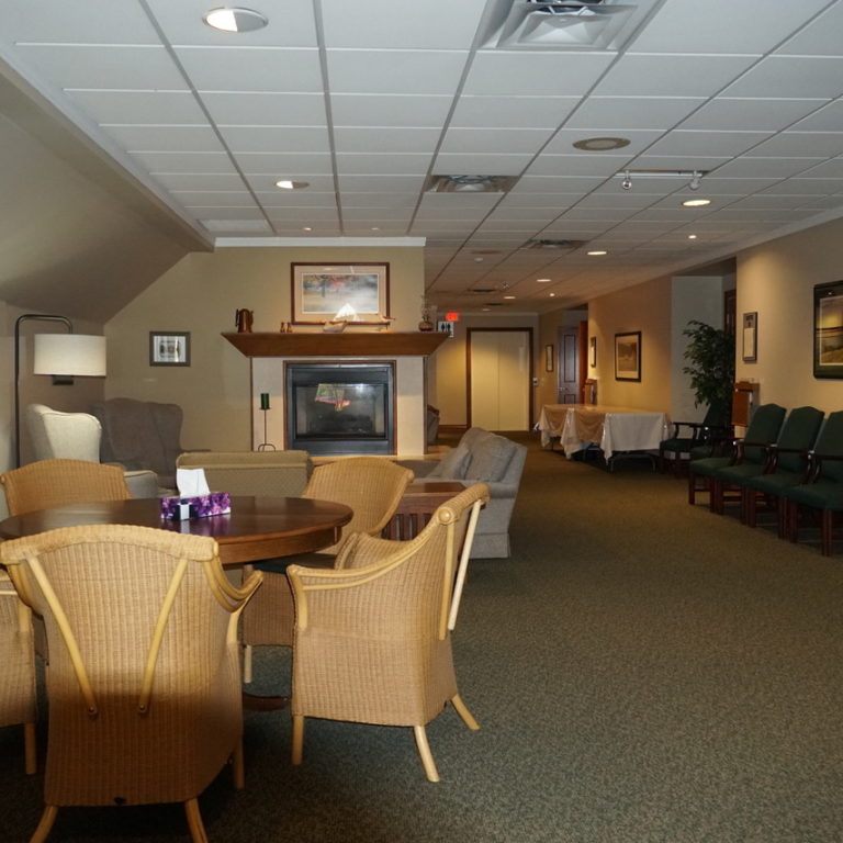 Carpeted lobby with tables and chairs, and picture frames hanging on the walls.