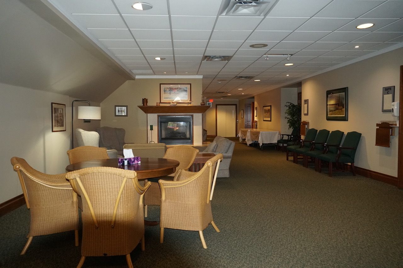Carpeted lobby with tables and chairs, and picture frames hanging on the walls.