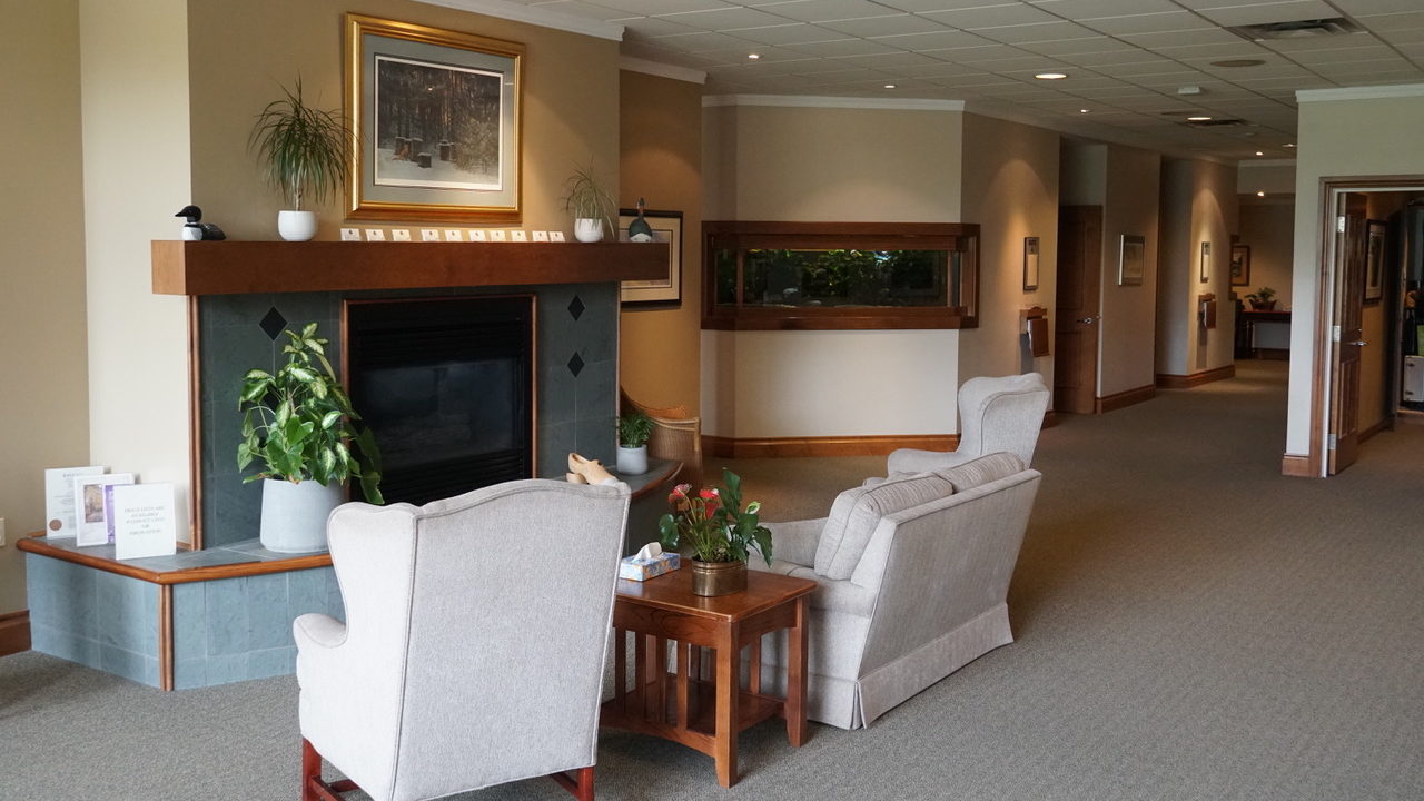 Funeral home lobby with chairs, tables and plants.