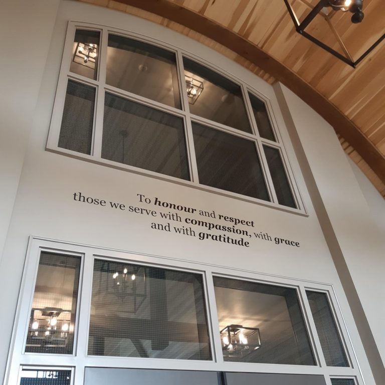 Image of a funeral home mission statement printed on the wall in the middle of two glass windows.