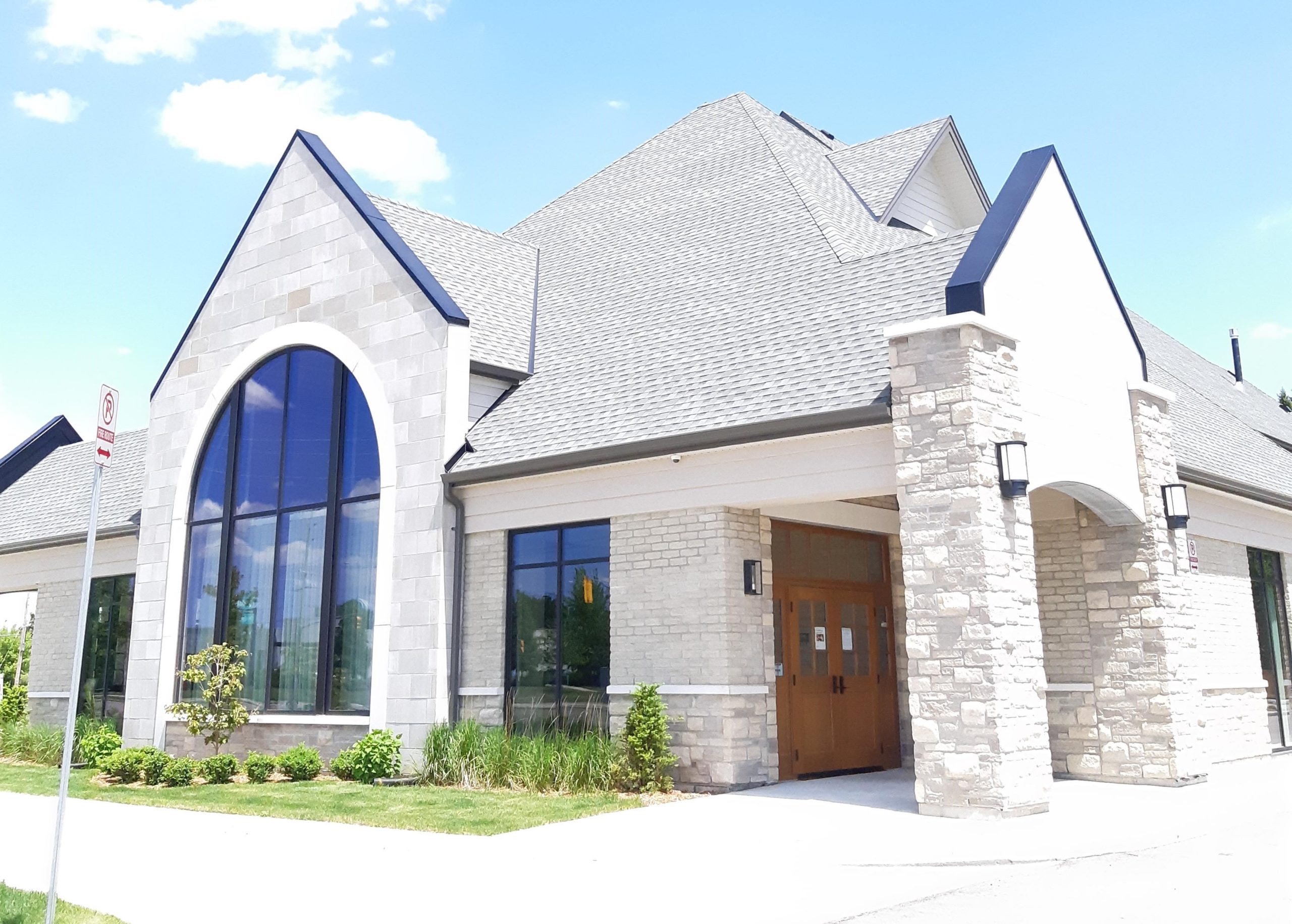 Exterior of a funeral home, with large glass windows and large wooden entrance doors.